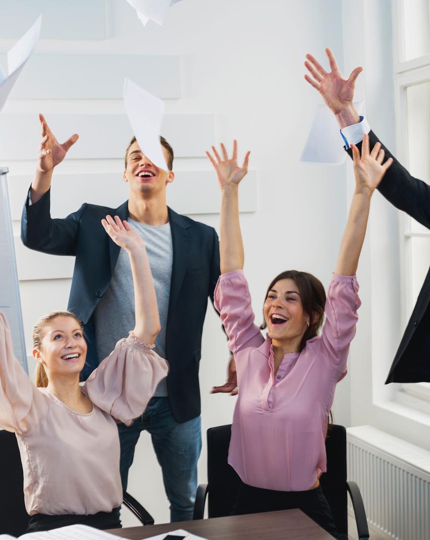 Businesspeople throwing papers in the air at office